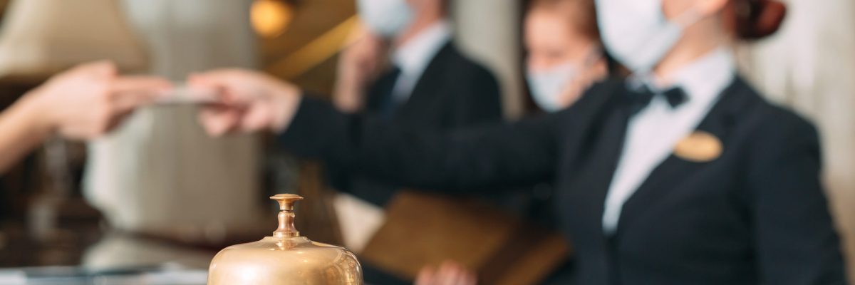 Check in hotel. receptionist at counter in hotel wearing medical masks as precaution against virus. Young woman on a business trip doing check-in at the hotel